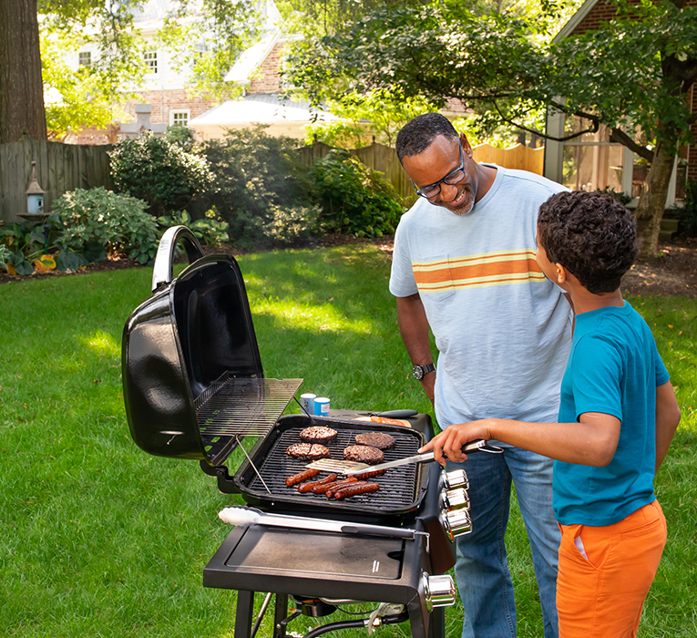 dad and son grilling on lawn